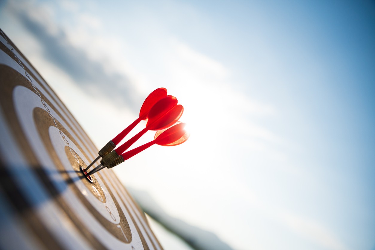 red darts on dart board with blue sky in the back ground