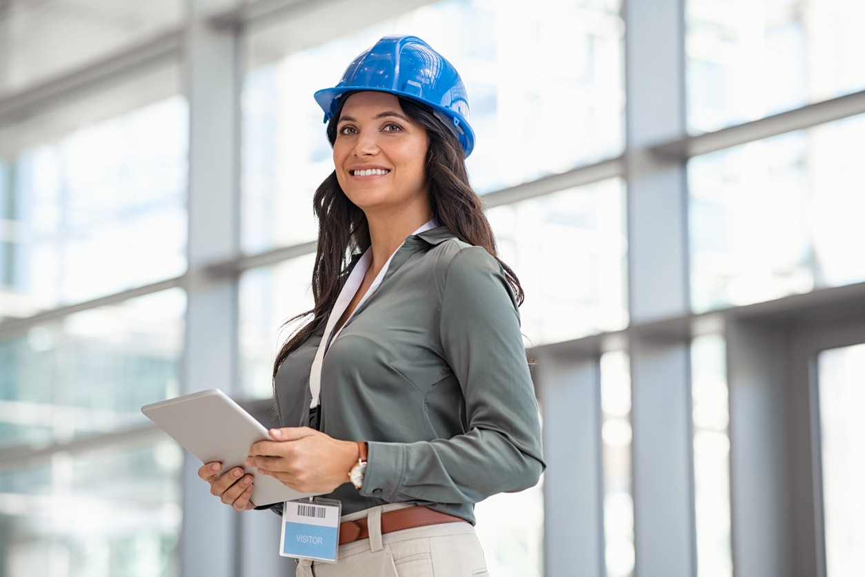 Beautiful mid adult woman architect wearing blue hardhat at construction site
