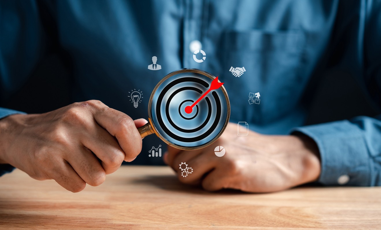 A man holding magnifying glass with target arrow in the middle