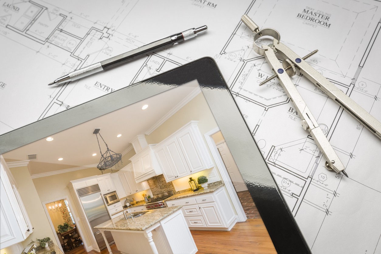 Computer Tablet Showing Finished Kitchen Sitting On House Plans With Pencil and Compass