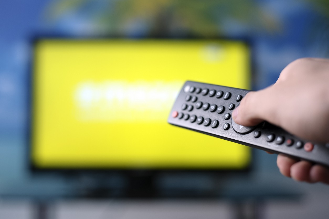 a person holding remote control and pointing on the tv