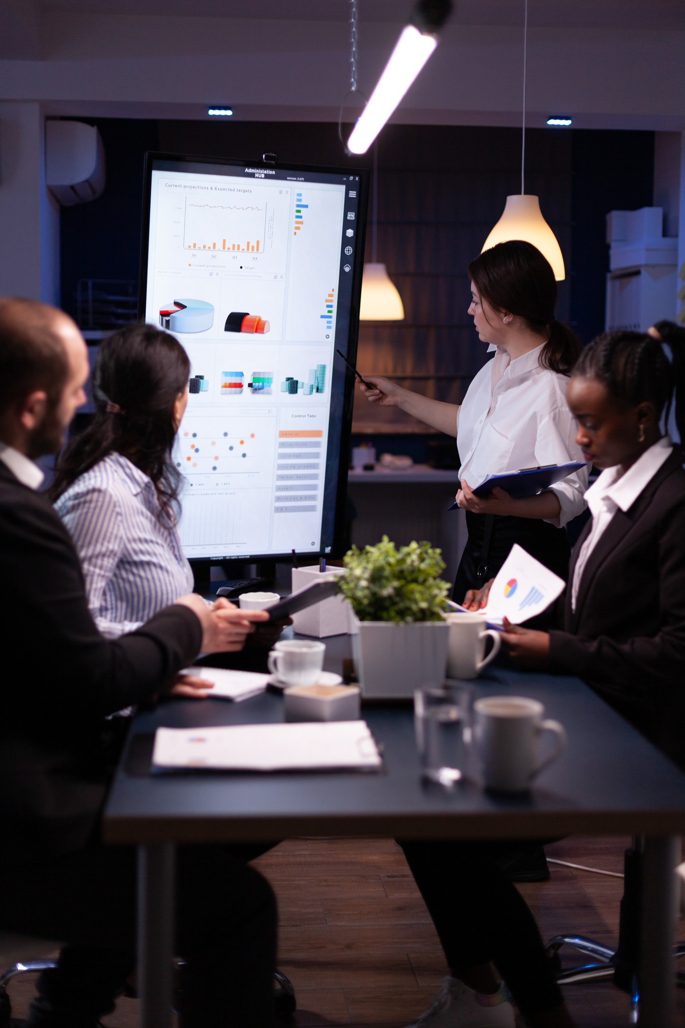 Team of magazine marketing experts standing around desk looking at graphs